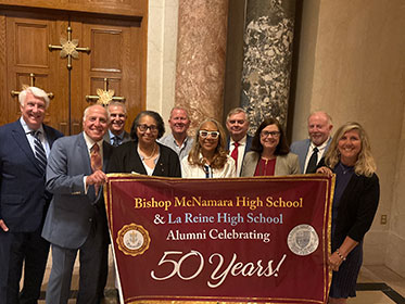 Bishop McNamara High School alumni holding up a sign celebrating 50 years